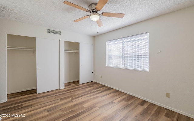 5319 S Via Galapagos, Tucson, AZ 85706 - unfurnished bedroom with two closets, wood finished floors, a textured ceiling, baseboards, and a ceiling fan