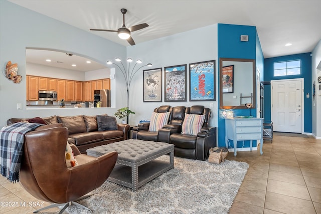 living area with a ceiling fan, arched walkways, and light tile patterned floors