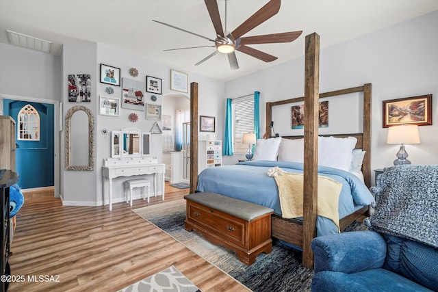 bedroom featuring visible vents, a ceiling fan, arched walkways, light wood-style floors, and baseboards