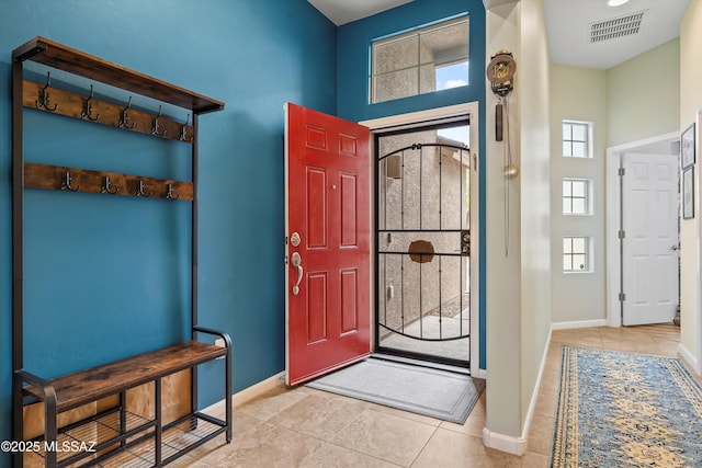 tiled entrance foyer featuring baseboards, visible vents, and a towering ceiling