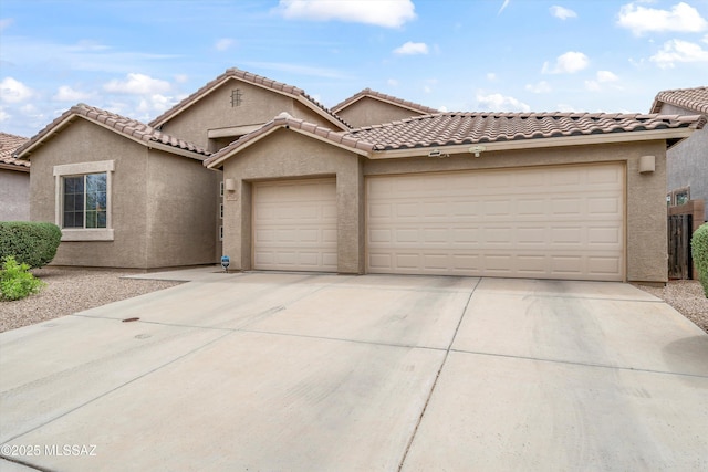 view of front of property featuring a tiled roof, an attached garage, concrete driveway, and stucco siding