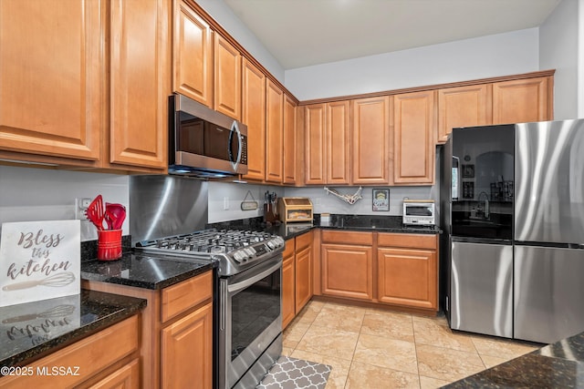 kitchen with brown cabinets, appliances with stainless steel finishes, dark stone countertops, and a toaster