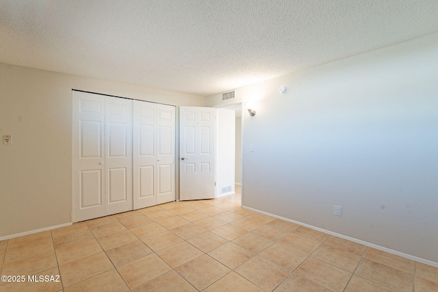 7617 E Morelos Pl, Tucson, AZ 85710 - unfurnished bedroom featuring a textured ceiling, light tile patterned floors, a closet, and baseboards