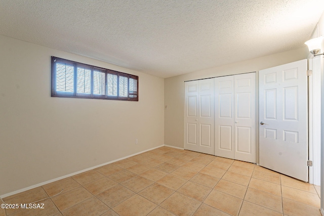 7617 E Morelos Pl, Tucson, AZ 85710 - unfurnished bedroom with light tile patterned floors, a textured ceiling, a closet, and baseboards