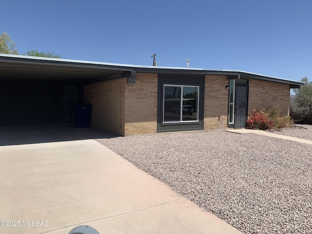7617 E Morelos Pl, Tucson, AZ 85710 - view of front facade featuring brick siding, concrete driveway, and a carport
