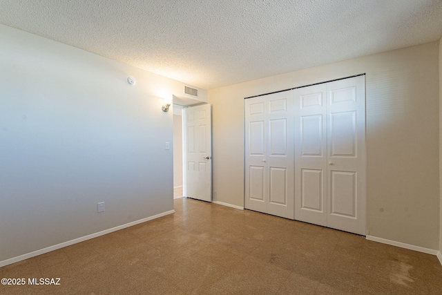 7617 E Morelos Pl, Tucson, AZ 85710 - unfurnished bedroom featuring a textured ceiling, baseboards, a closet, and tile patterned floors