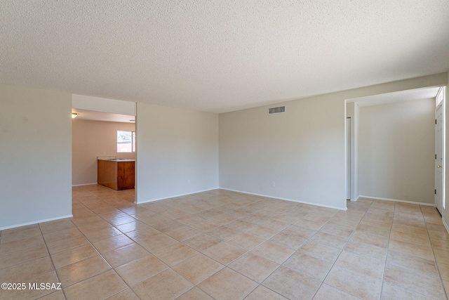 7617 E Morelos Pl, Tucson, AZ 85710 - empty room featuring light tile patterned flooring, a textured ceiling, and baseboards