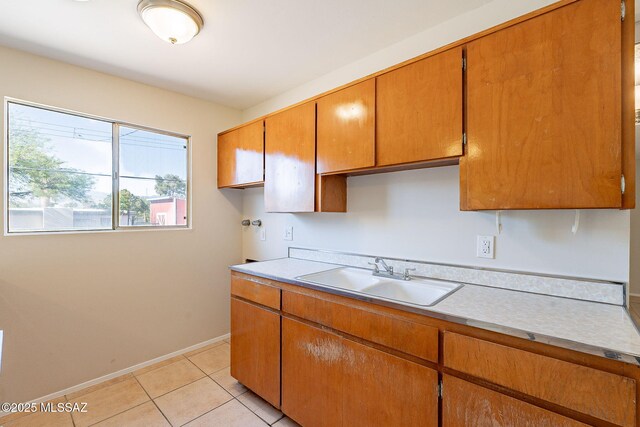 7617 E Morelos Pl, Tucson, AZ 85710 - kitchen with a sink, light countertops, light tile patterned floors, baseboards, and brown cabinets