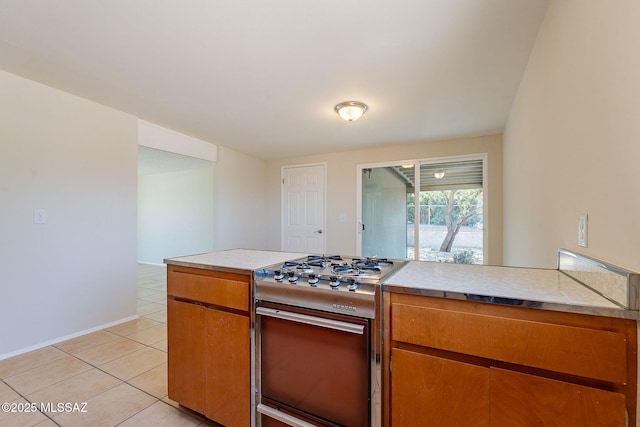 7617 E Morelos Pl, Tucson, AZ 85710 - kitchen featuring double oven range, brown cabinets, light tile patterned floors, light countertops, and baseboards