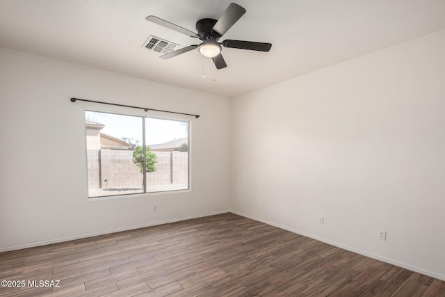 spare room featuring a ceiling fan, baseboards, visible vents, and wood finished floors