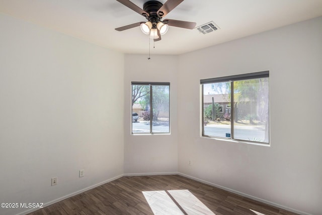 unfurnished room featuring ceiling fan, plenty of natural light, wood finished floors, and visible vents