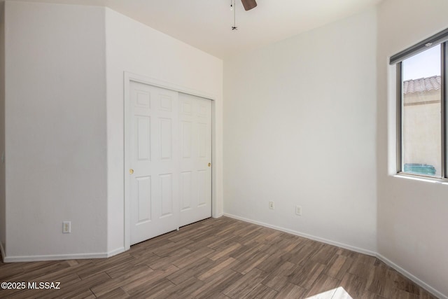 unfurnished bedroom with baseboards, wood finished floors, and a closet