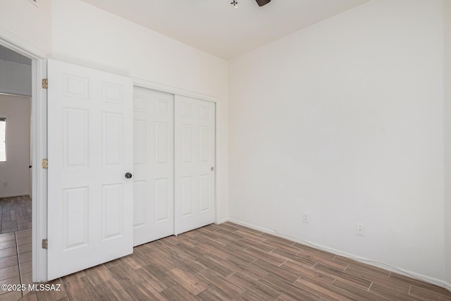 unfurnished bedroom with baseboards, wood finished floors, and a closet