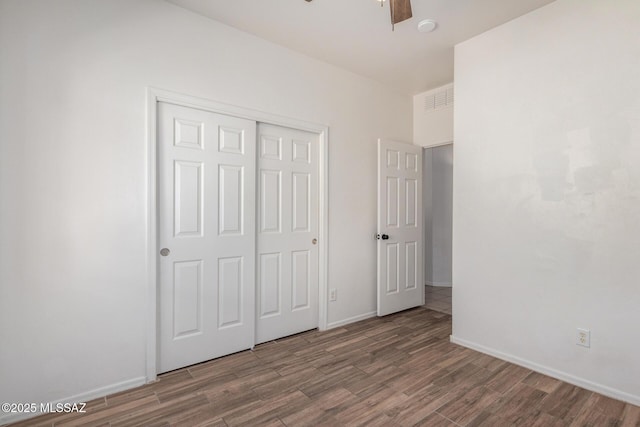 unfurnished bedroom featuring baseboards, ceiling fan, wood finished floors, and a closet