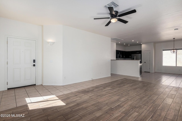 unfurnished living room with ceiling fan, visible vents, baseboards, and wood tiled floor