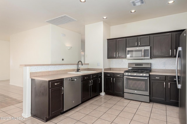 kitchen with a sink, light countertops, stainless steel appliances, a peninsula, and visible vents