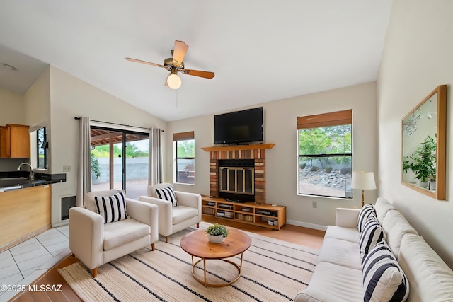 living area with ceiling fan, a brick fireplace, light tile patterned floors, baseboards, and lofted ceiling