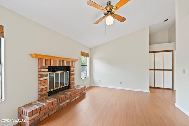 unfurnished living room with ceiling fan, a fireplace, baseboards, wood finished floors, and lofted ceiling