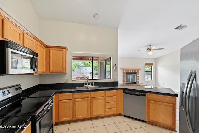kitchen featuring brown cabinetry, a ceiling fan, visible vents, a sink, and stainless steel appliances