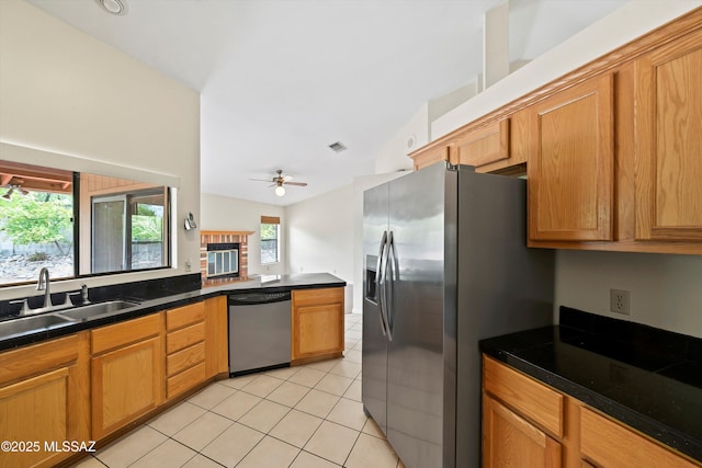 kitchen with a sink, appliances with stainless steel finishes, dark countertops, and light tile patterned flooring