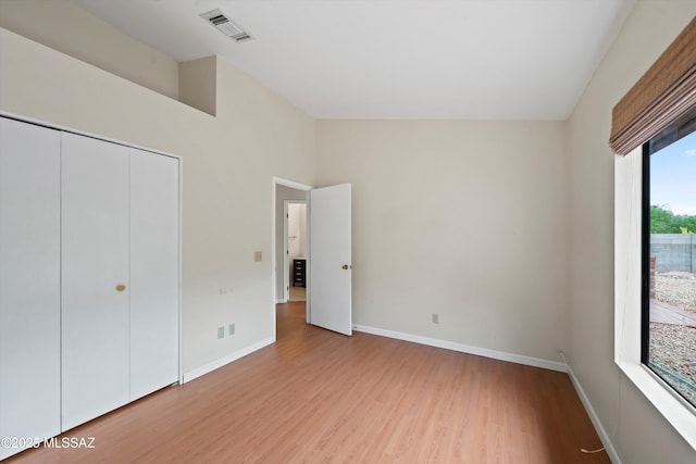 unfurnished bedroom featuring visible vents, baseboards, wood finished floors, and a closet
