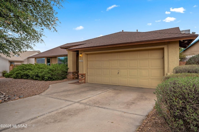 ranch-style home with a shingled roof, an attached garage, concrete driveway, and stucco siding