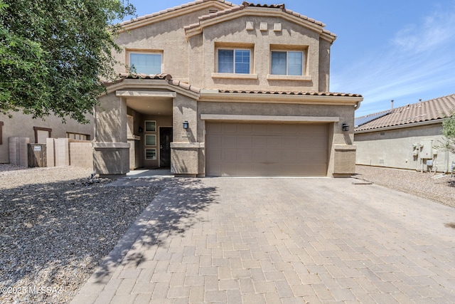 mediterranean / spanish-style home with a garage, stucco siding, a tiled roof, and decorative driveway