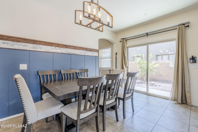 dining room with a chandelier, arched walkways, and light tile patterned floors