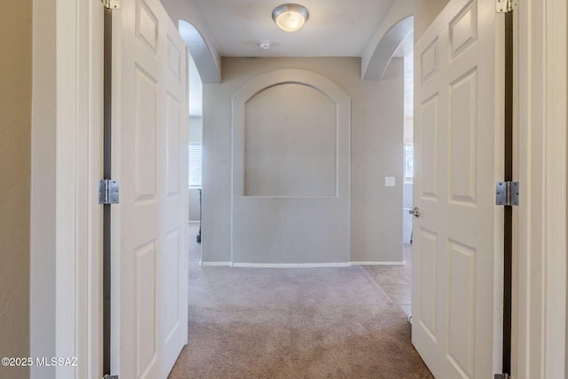 corridor with baseboards and light carpet