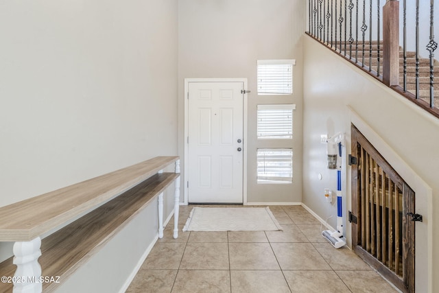 entryway with a high ceiling, baseboards, and tile patterned flooring
