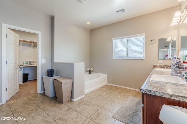 bathroom with a garden tub, visible vents, a sink, tile patterned floors, and baseboards