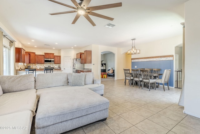living room featuring ceiling fan with notable chandelier, light tile patterned floors, arched walkways, visible vents, and recessed lighting
