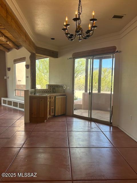 unfurnished dining area with visible vents, ornamental molding, a sink, light tile patterned floors, and a notable chandelier