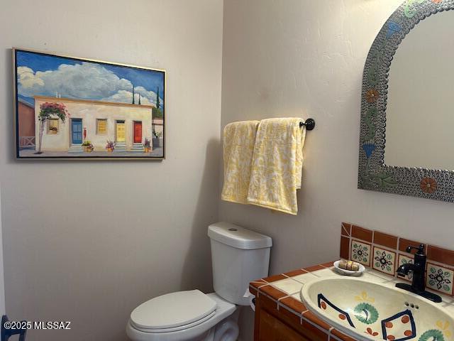 half bathroom featuring vanity and toilet