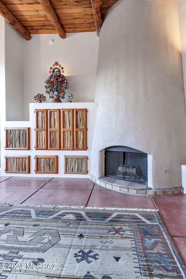unfurnished living room with beamed ceiling, a fireplace, wood ceiling, and concrete flooring
