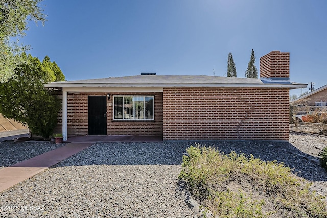 view of front of house featuring a chimney, fence, and brick siding