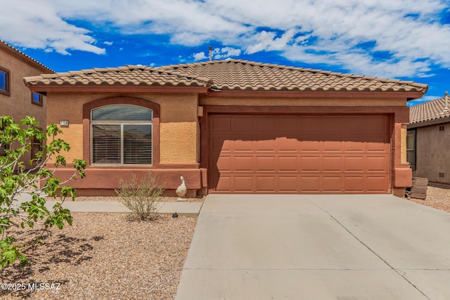mediterranean / spanish home featuring a garage, driveway, a tiled roof, and stucco siding