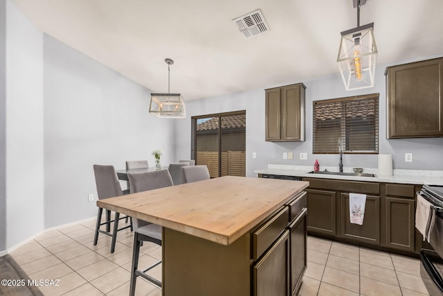 kitchen with light tile patterned floors, visible vents, wooden counters, and a sink