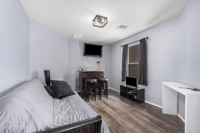 bedroom with wood finished floors, visible vents, and baseboards