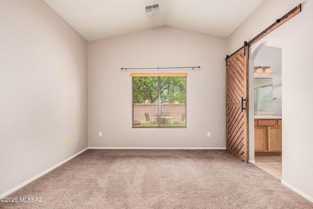 unfurnished bedroom featuring a barn door, vaulted ceiling, light carpet, baseboards, and visible vents
