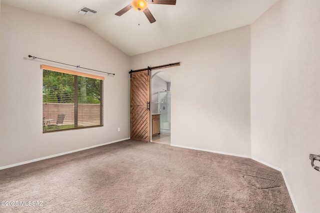 carpeted spare room featuring a barn door, baseboards, visible vents, lofted ceiling, and a ceiling fan