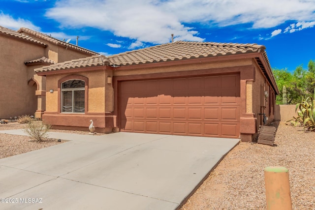 mediterranean / spanish-style home featuring an attached garage, a tiled roof, driveway, and stucco siding