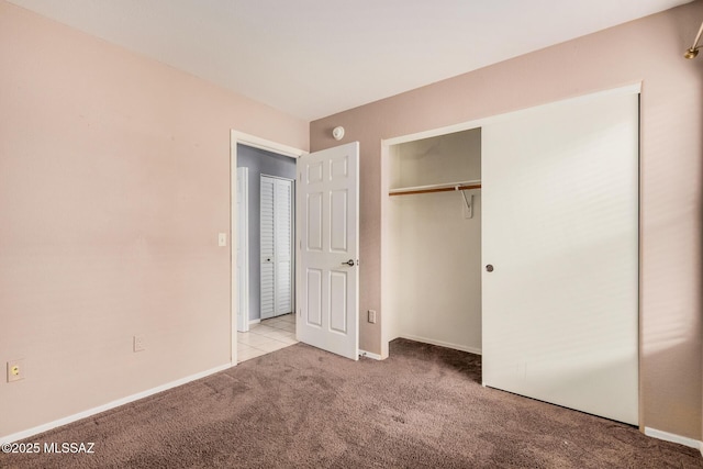 unfurnished bedroom featuring baseboards, carpet floors, and a closet