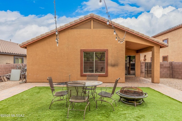 back of property with stucco siding, fence, a yard, and an outdoor fire pit