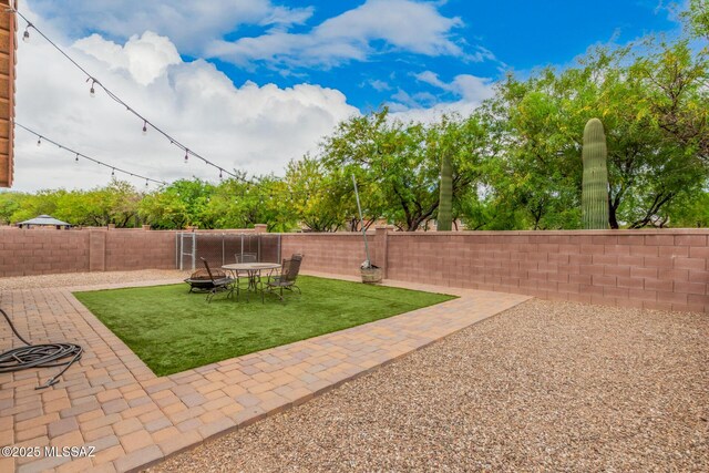 view of yard with a fenced backyard, a patio, and an outdoor fire pit