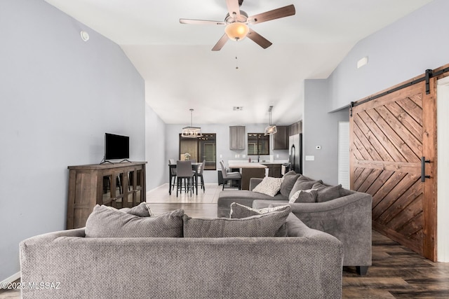living area with a barn door, dark wood finished floors, lofted ceiling, and a ceiling fan