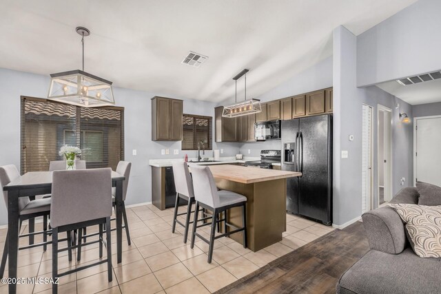 kitchen featuring visible vents, a sink, black appliances, butcher block countertops, and open floor plan