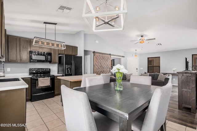dining area featuring a barn door, lofted ceiling, visible vents, and light tile patterned floors