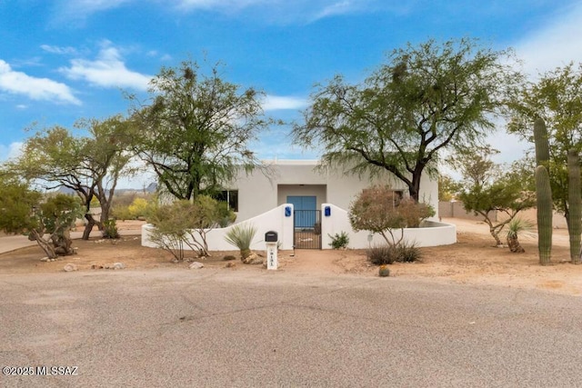 view of front of home featuring stucco siding, a gate, and a fenced front yard