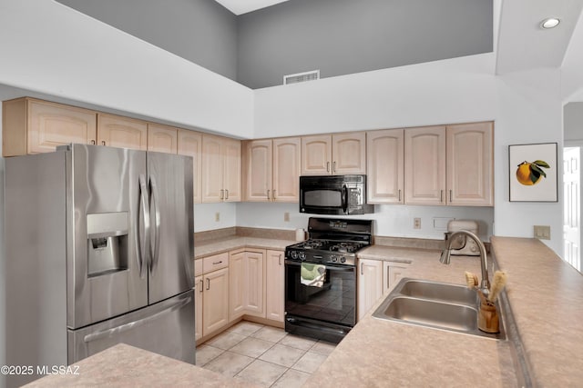 kitchen with light brown cabinets, a sink, black appliances, light countertops, and visible vents